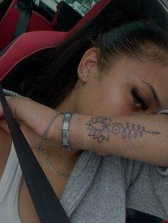 a woman with tattoos on her arm sitting in a car