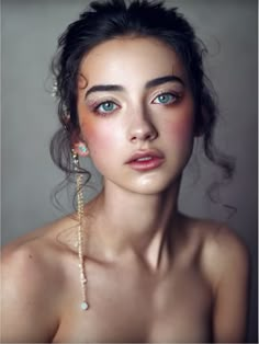 a woman with blue eyes wearing gold jewelry