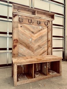 a bench made out of wooden planks in front of a wall with hooks on it