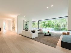 a large living room with hardwood floors and white furniture in front of sliding glass doors