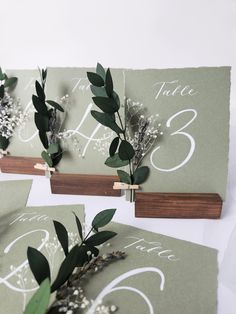 the table numbers are decorated with flowers and greenery