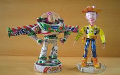 two tinker toys are standing next to each other on a wooden surface, one is wearing a cowboy hat and the other is holding a candy bar