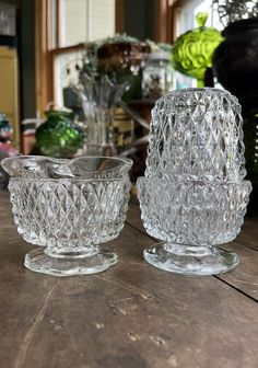 two clear glass bowls sitting on top of a wooden table next to eachother