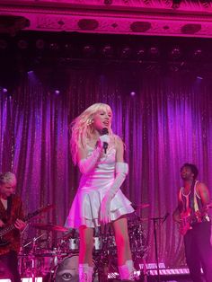 lady in white dress singing on stage with band