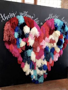 there is a heart made out of yarns on the blackboard with words above it