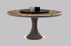 a round table with a black plate on top and a silver vase sitting on it