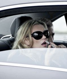 a woman talking on a cell phone while sitting in a car next to a man