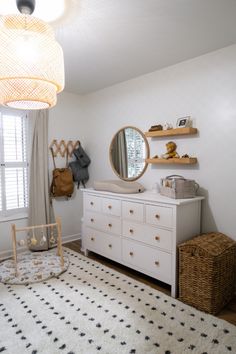 a baby's room with a white dresser and black and white rug