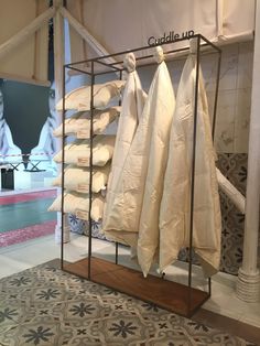 a display case filled with lots of white clothing hanging on clothes racks next to a rug