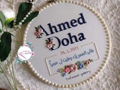 a white embroidered sign with flowers on it and a lace doily next to it