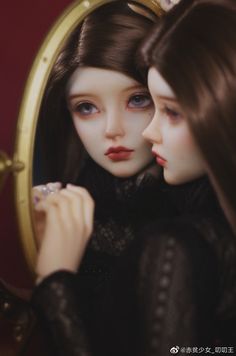 two dolls that are looking at each other in front of a magnifying mirror