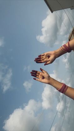 three hands reaching up into the air with clouds in the background