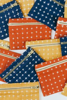 several small zippered pouches with white crosses on orange, blue and yellow fabric