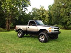 a truck parked in the grass near trees