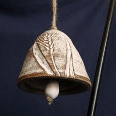 a bell hanging from a rope with a bird on it's side and another item in the background