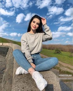 a woman sitting on top of a cement wall