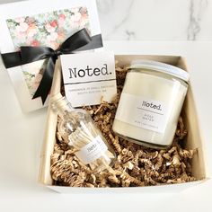 an open box containing a candle, glass jar and notecard