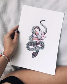 a woman is holding up a card with a snake and flower on it