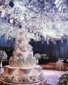 a large wedding cake sitting on top of a table under a chandelier filled with flowers