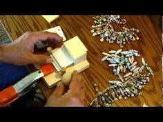 a person is making necklaces with beads on a wooden table next to other items