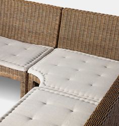 a wicker couch with white cushions on it