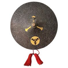 a black and yellow clock with red tassels hanging from it's side