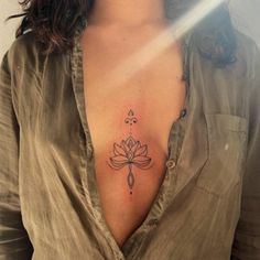 a woman's chest with a lotus tattoo on her left side and an arrow in the middle