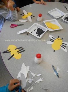 children are sitting at a table with paper cut out of animals and birds on it