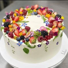 a white cake topped with fresh fruit and flowers