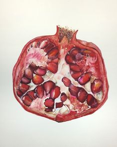 a pomegranate cut in half on top of a white surface with other fruits and vegetables