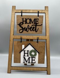 a sign that says home sweet and a house with a wreath hanging on the front