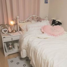 a white bed sitting next to a night stand with a stuffed animal on top of it