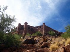 a castle like building on top of a rocky hill with trees in the foreground