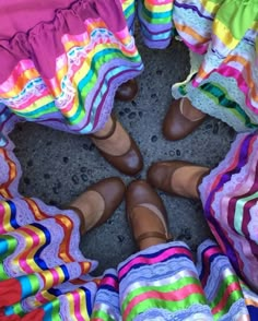 several people wearing colorful clothing standing in a circle with their feet up on the ground