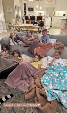 a group of children laying on top of a couch covered in blankets and blankets next to each other