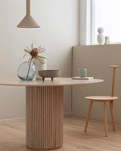 a table with a vase on it next to a chair