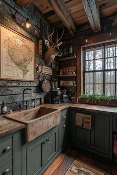 a rustic kitchen with green cabinets and wood flooring, an antler head on the wall