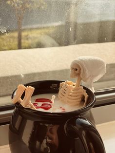 a fake skeleton sitting in a bowl of liquid