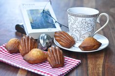 some muffins on a plate next to a coffee cup and an mp3 player