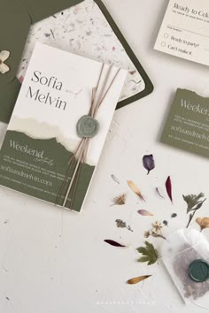 the wedding stationery is laid out on top of the table with flowers and buttons