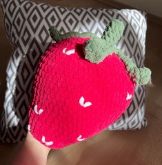 a knitted strawberry pillow sitting on top of a wooden floor