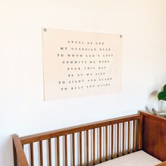 a wooden crib with a sign hanging on the wall above it and a plant