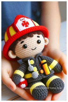 a small crocheted fireman doll sitting in someone's hand