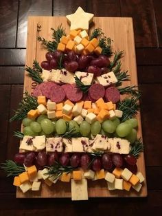 a christmas tree made out of cheese, grapes and meats on a cutting board