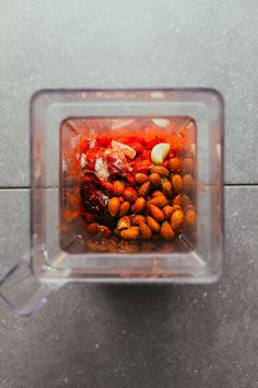 a blender filled with lots of food on top of a cement floor next to a tile wall