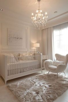 a white baby's room with a chandelier, chair and crib