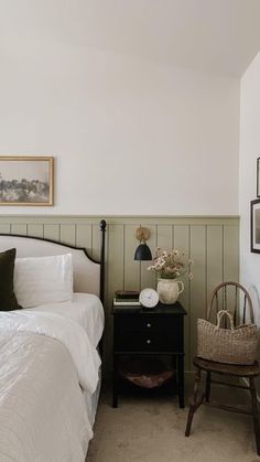 a white bed sitting next to a wooden table with a basket on top of it