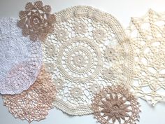 several crocheted doily are laid out on a white tablecloth with different colors