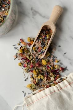 a wooden scoop filled with lots of different types of flowers next to a cloth bag