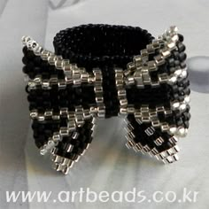 a close up of a black and silver beaded bow on a white cloth background